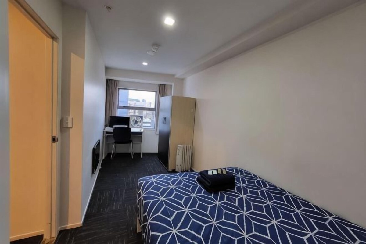 Ein Hotelzimmer mit Bett, Schreibtisch und Blick auf die Stadt.