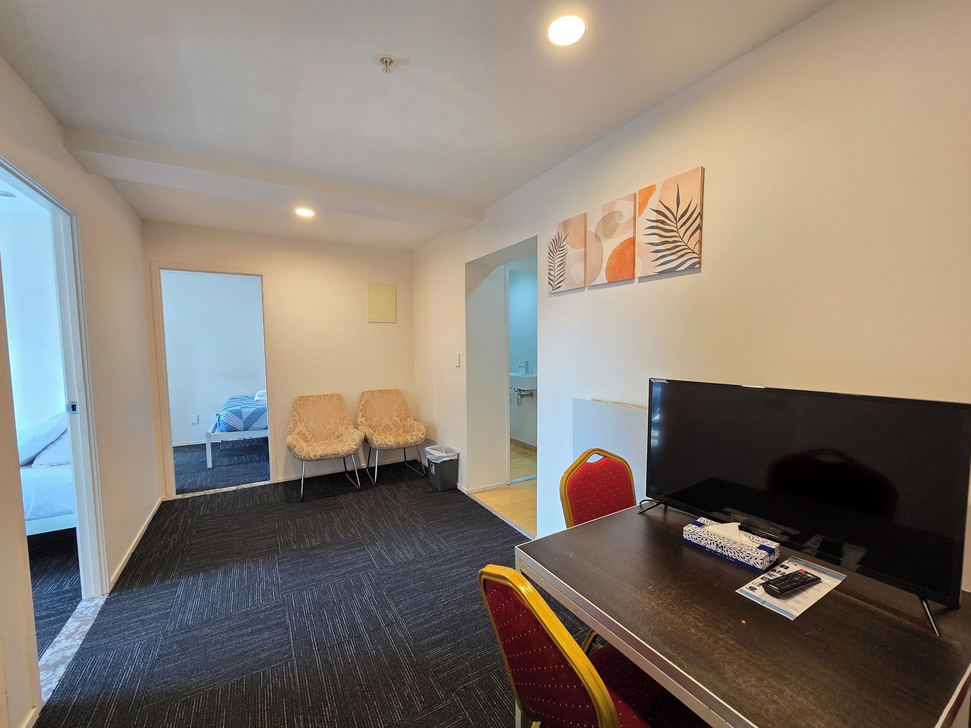Une chambre d’hôtel équipée d’un lit, de deux chaises, d’une télévision et d’un bureau avec une télécommande.