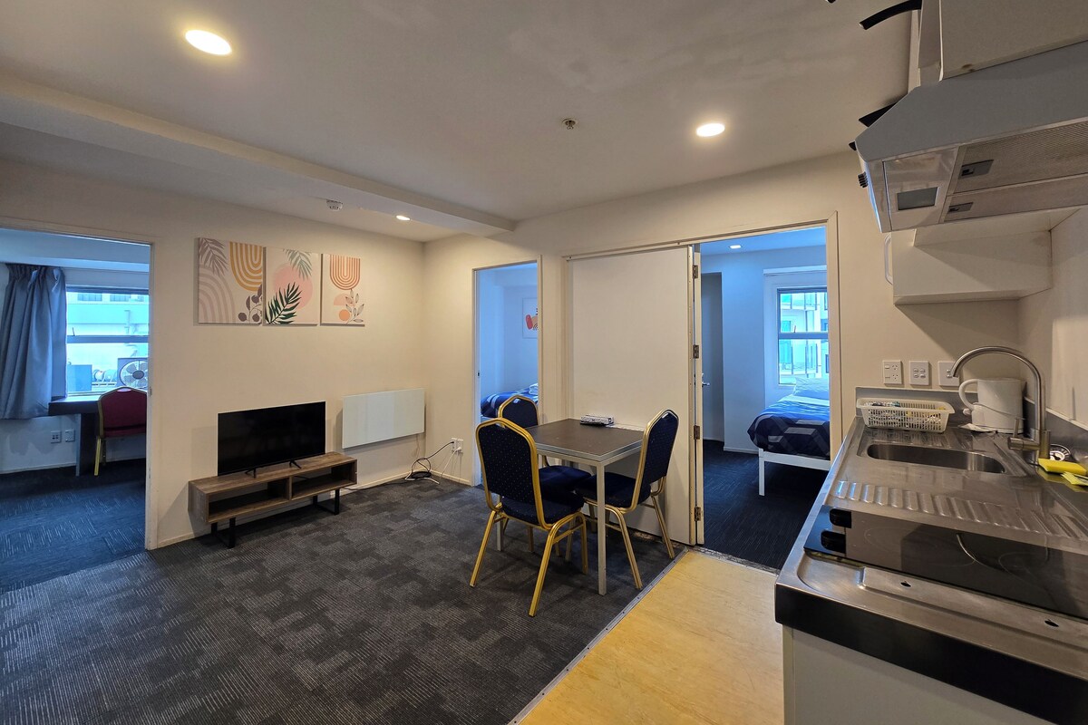 Habitación de hotel compacta con kitchenette, zona de comedor y cama.