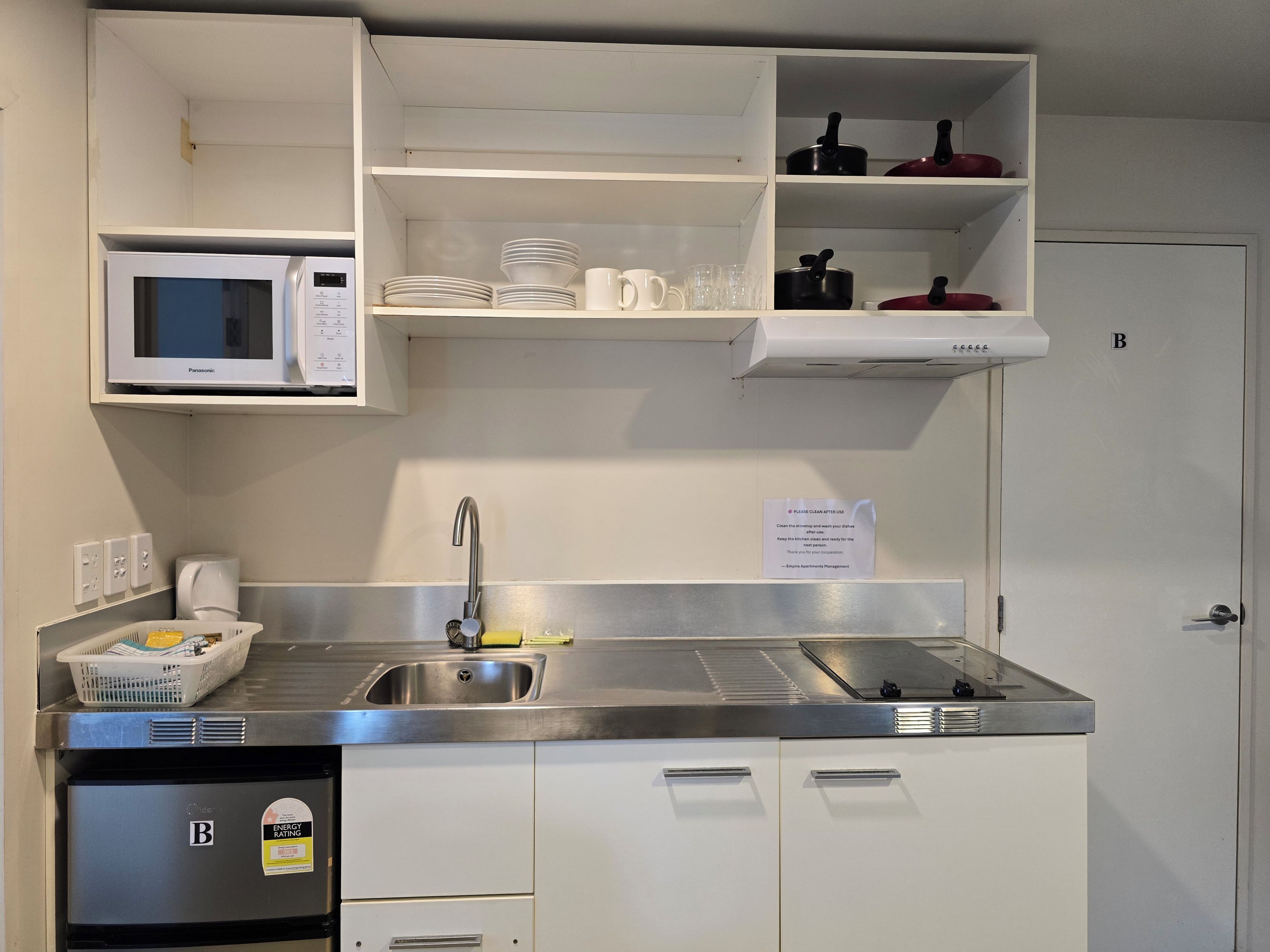Une cuisine compacte équipée d’un four à micro-ondes, d’un évier et de placards de rangement.