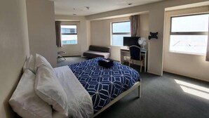 Una habitación de hotel con cama, escritorio, sillón, sofá y ventana.