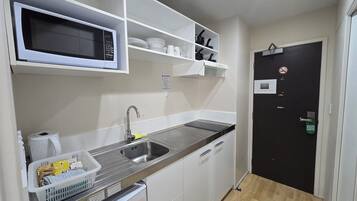 A compact kitchen with a microwave, sink, and storage shelves.