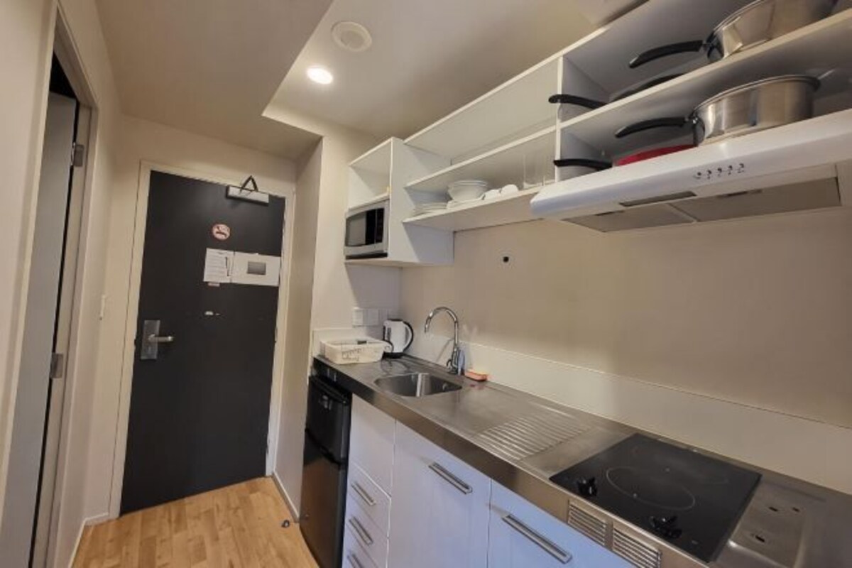 A compact kitchen with a microwave, stove, and white cabinets.