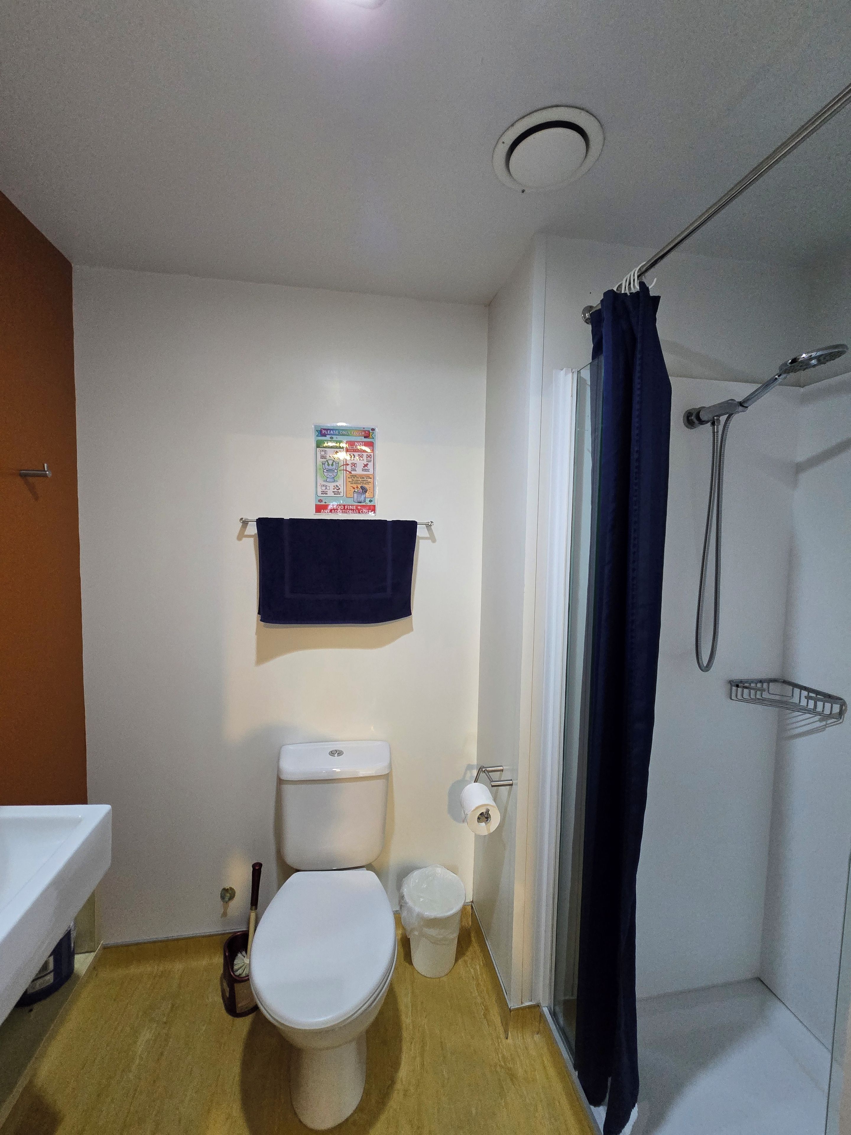 Ein kleines Badezimmer mit Toilette, Dusche, Handtuchhalter und Mülleimer.
