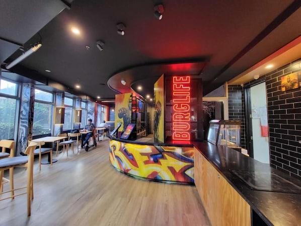 Interior de restaurante con una barra curva, mesas y sillas de madera.