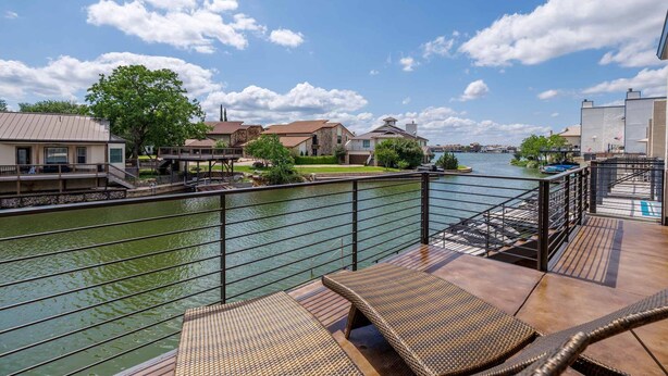 Une propriété située au bord de l’eau, dotée d’une terrasse, de chaises longues et offrant une vue sur la rivière.