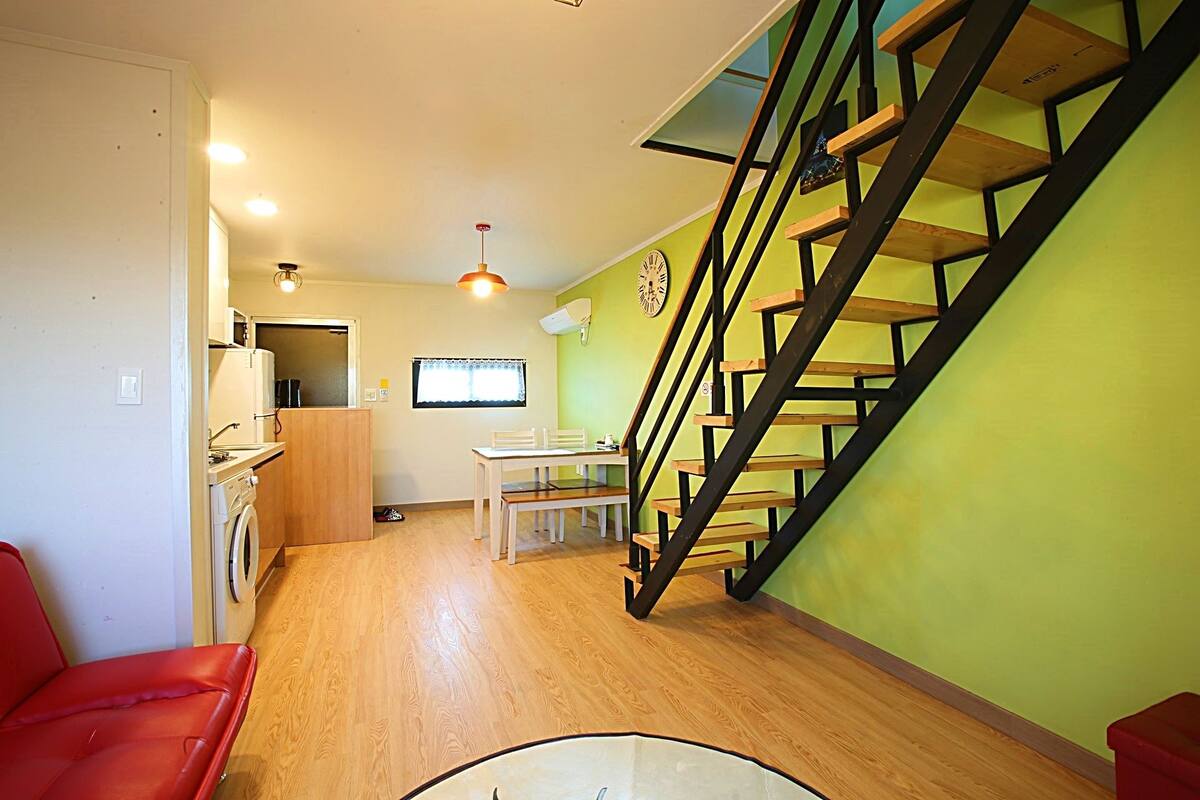 A compact living space with a kitchen, dining area, and a staircase.