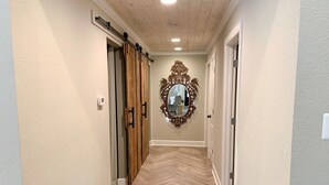 Un couloir doté d’un parquet en chevrons, d’une porte coulissante de style rustique et d’un miroir orné d’un cadre travaillé.