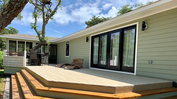 Une maison dotée d’un patio couvert, de mobilier d’extérieur et d’une grande porte-fenêtre coulissante.