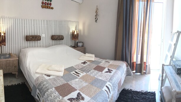 Een slaapkamer met een bed, nachtkastjes, een dressoir, een spiegel en een muur met een droomvanger en een bord.
