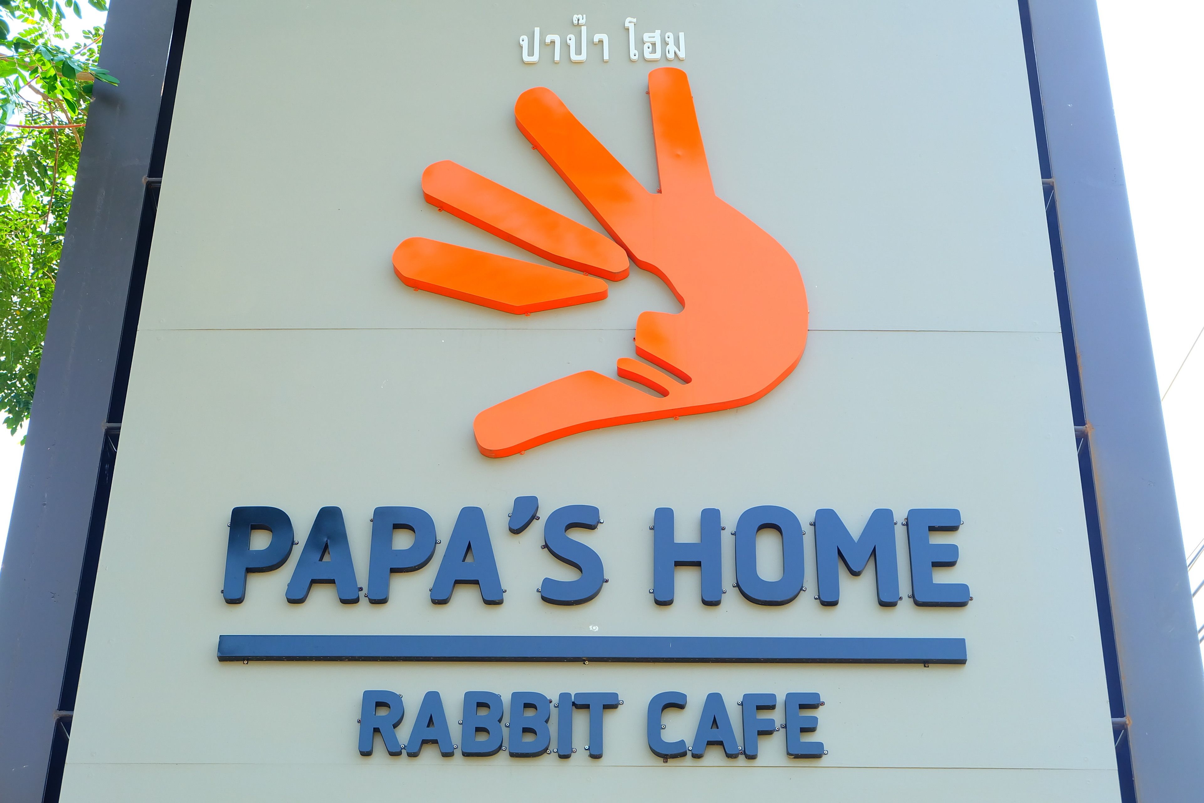 A sign for Papa's Home Rabbit Cafe with a large orange hand symbol.