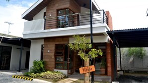 A two-story building with a balcony, a sign reading "Vania," and a small tree in the foreground. - The Tavern Villas at  Orchid Gardens (Bacolor)