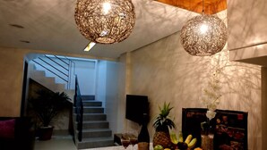 A modern interior with a staircase, a dining area with fruit and a bottle, and two spherical hanging lights. - The Tavern Villas at  Orchid Gardens (Bacolor)
