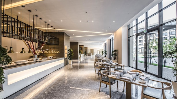 A modern hotel lobby with a long reception desk, seating area, and large windows offering views of the city. - Q-Box Hotel Shanghai Sanjiagang (Shanghai)