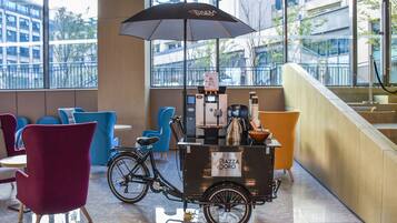 A modern indoor seating area with a coffee cart labeled "Piazza D'oro Espresso" and a bicycle.