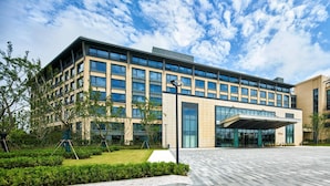 A modern building with a large entrance, glass doors, and a covered area. - Q-Box Hotel Shanghai Sanjiagang (Shanghai)