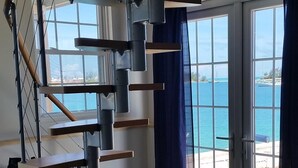 A spiral staircase with wooden steps and metal railings, leading to a balcony with a view of the sea. - Stunning sunsets, turtle watching, longtails wheeling and glow worms .... (Somerset Village)