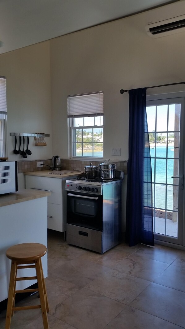 Une cuisine équipée d’une cuisinière, d’un four et offrant une vue sur la mer par une fenêtre.