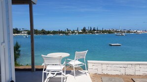 A patio with two white chairs and a table overlooking a marina with boats and a coastal town in the background. - Stunning sunsets, turtle watching, longtails wheeling and glow worms .... (Somerset Village)