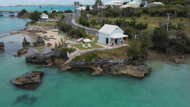 A coastal property with a white building, a paved driveway, and a grassy area with lounge chairs. - Stunning sunsets, turtle watching, longtails wheeling and glow worms .... (Somerset Village)