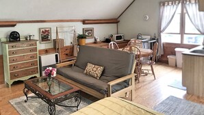 Ett mysigt vardagsrum med en soffa, ett soffbord och en matplats. Köket är utrustat med en mikrovågsugn och en diskho.