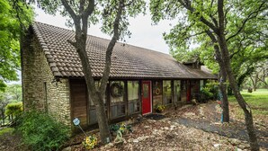 A rustic cabin with a stone exterior, a tiled roof, and a red door.