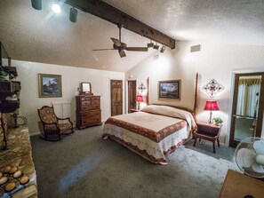Ein Schlafzimmer mit einem großen Bett, einer Holzkommode, einem Sessel und einem Deckenventilator.