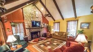 A cozy living room with a stone fireplace, a television, and comfortable seating.