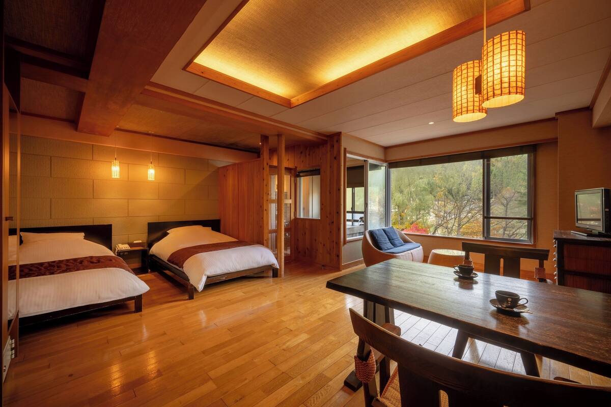 Een hotelkamer met twee bedden, een eettafel en een televisie.