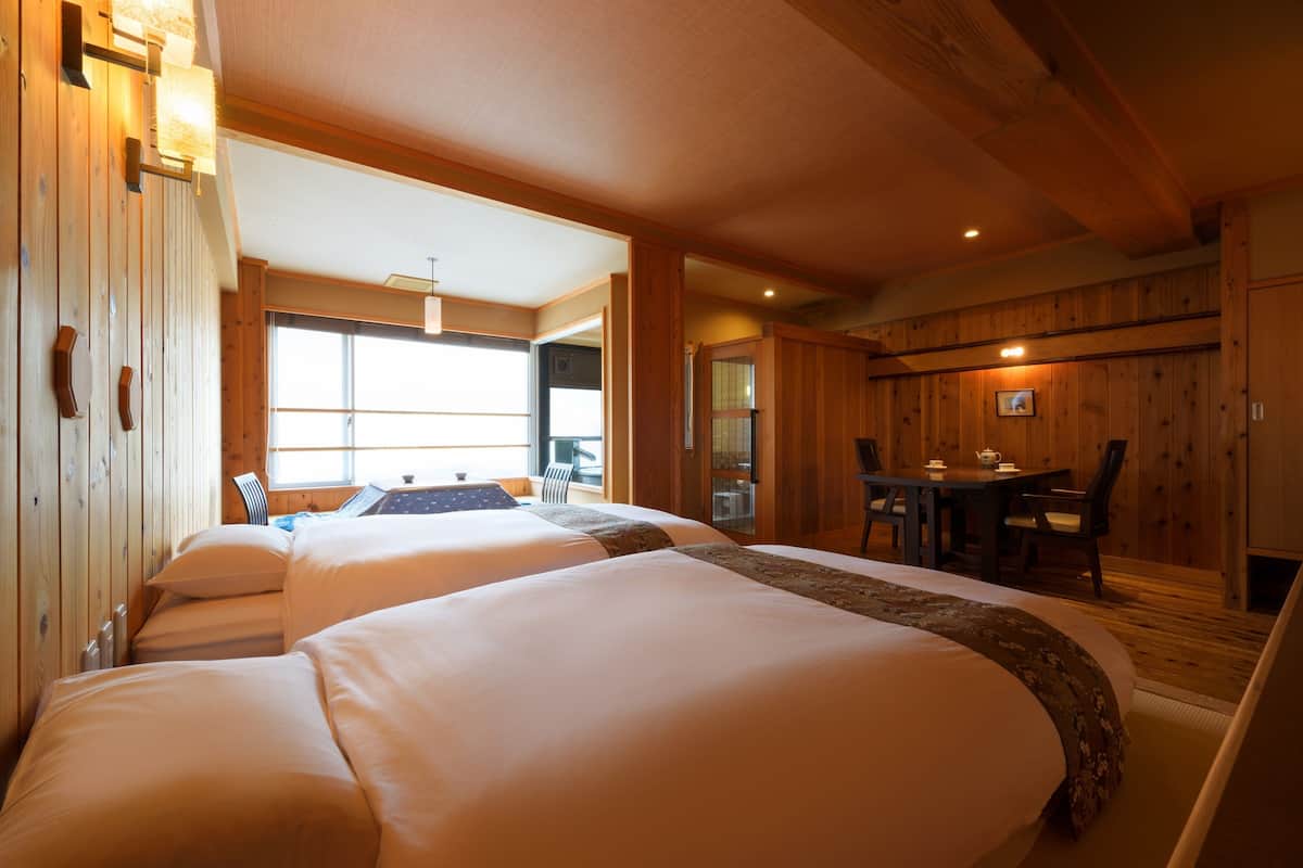 Een hotelkamer met twee bedden, een eettafel met stoelen en uitzicht op het landschap.