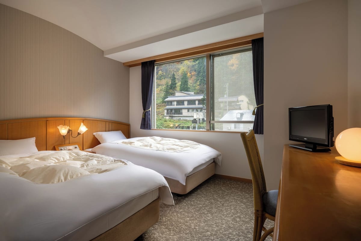 Een hotelkamer met twee bedden, een televisie en een bureau.
