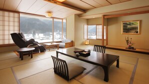 Een traditionele Japanse kamer met tatami vloerbedekking, een lage tafel, stoelen en een bank.
