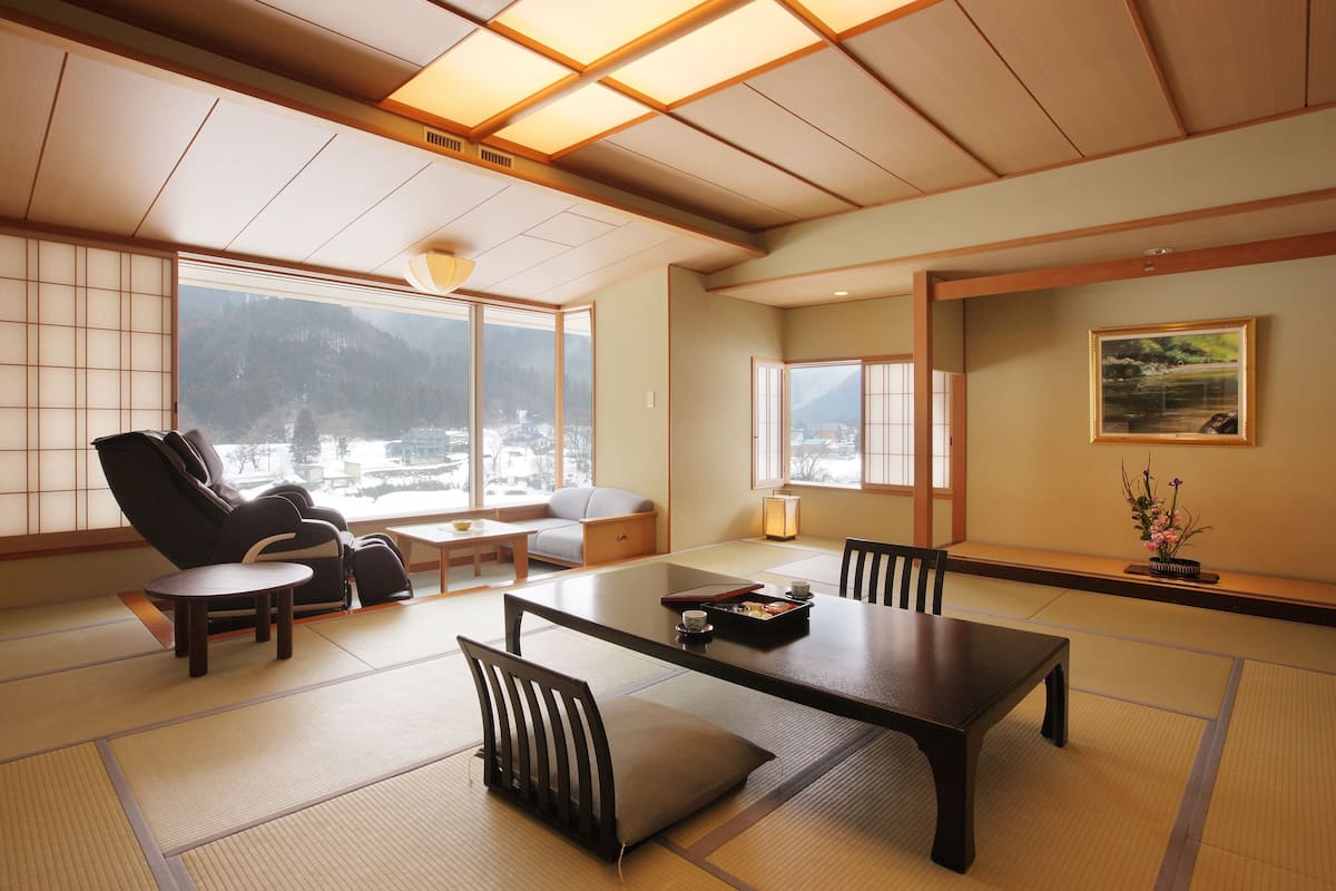 Een traditionele Japanse kamer met tatami vloerbedekking, een lage tafel, stoelen en een bank.