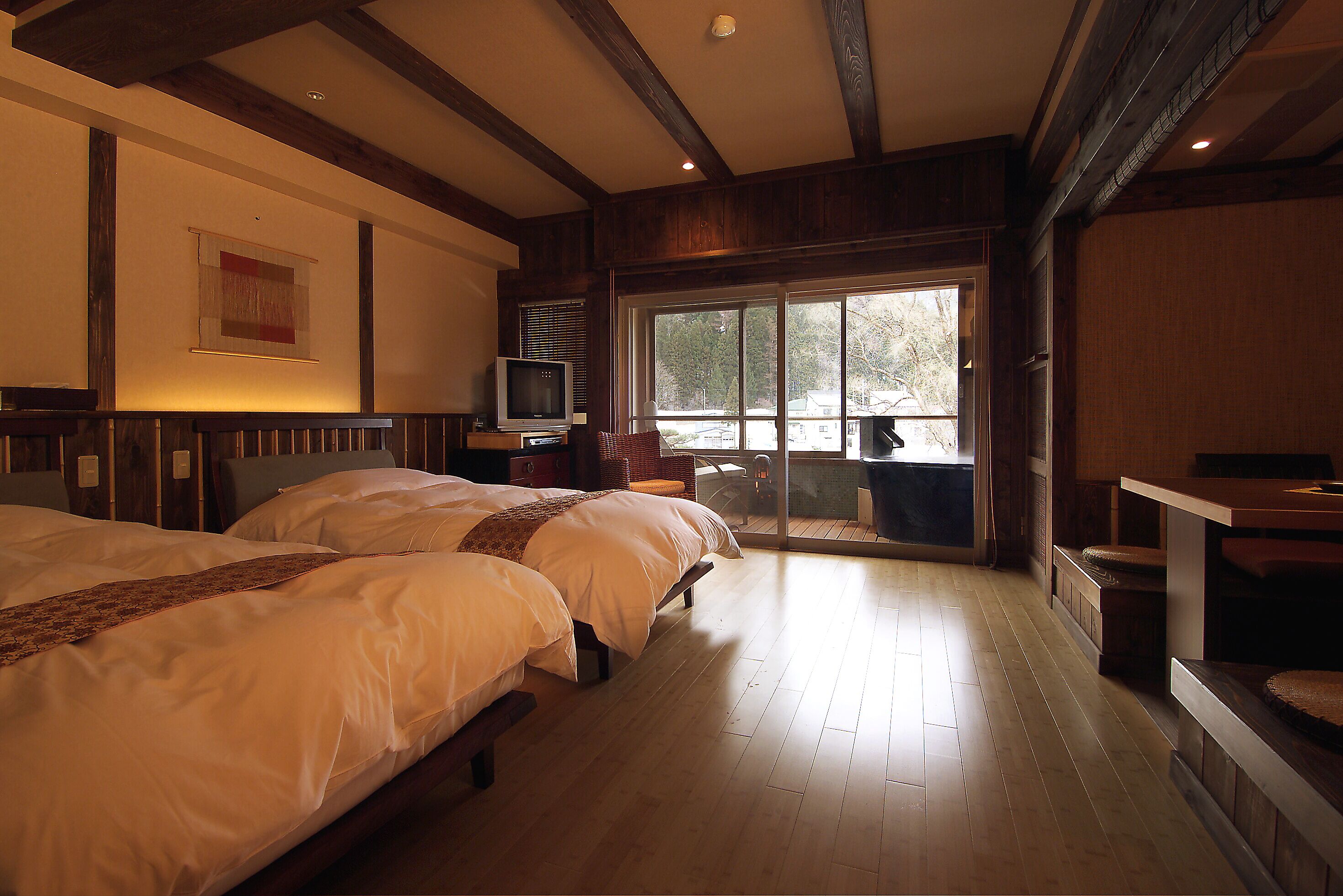 A hotel room with two beds, a television, and a large window.