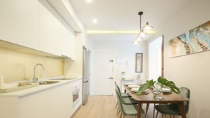 Eine moderne Küche mit weißen Schränken, einem Holztisch und einer Pendelleuchte.