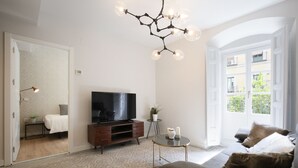 Ein modernes Wohnzimmer mit einer Couch, einem Fernseher, einem Couchtisch und einem Chandelier.