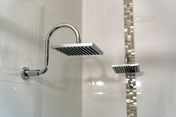 Un pommeau de douche moderne, doté d’un design incurvé et d’une tête carrée, fixé au mur et muni d’une finition brillante.