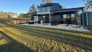 Une maison moderne dotée d’un patio couvert, de grandes fenêtres et offrant une vue sur le paysage environnant.