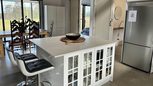 Une cuisine moderne dotée d’un îlot central, de meubles blancs et d’un réfrigérateur en acier inoxydable.
