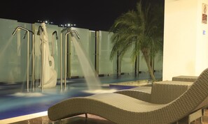 Un espace piscine doté de chaises longues et de plusieurs jets d’eau.