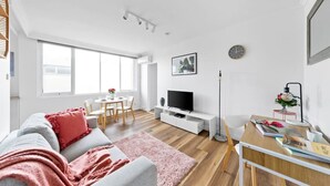 A modern living room with a sofa, TV, and dining area. - Bright & Sunny Oasis (Balaclava)