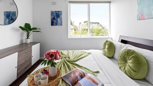 A modern bedroom with a bed, bedside tables, a dresser, and a window with a city view. - Bright & Sunny Oasis (Balaclava)