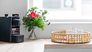 A modern kitchen with a coffee machine, a vase with flowers, and a woven basket. - Bright & Sunny Oasis (Balaclava)