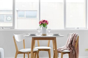 A dining area with a round table, four chairs, a vase with flowers, and a window with a view. - Bright & Sunny Oasis (Balaclava)