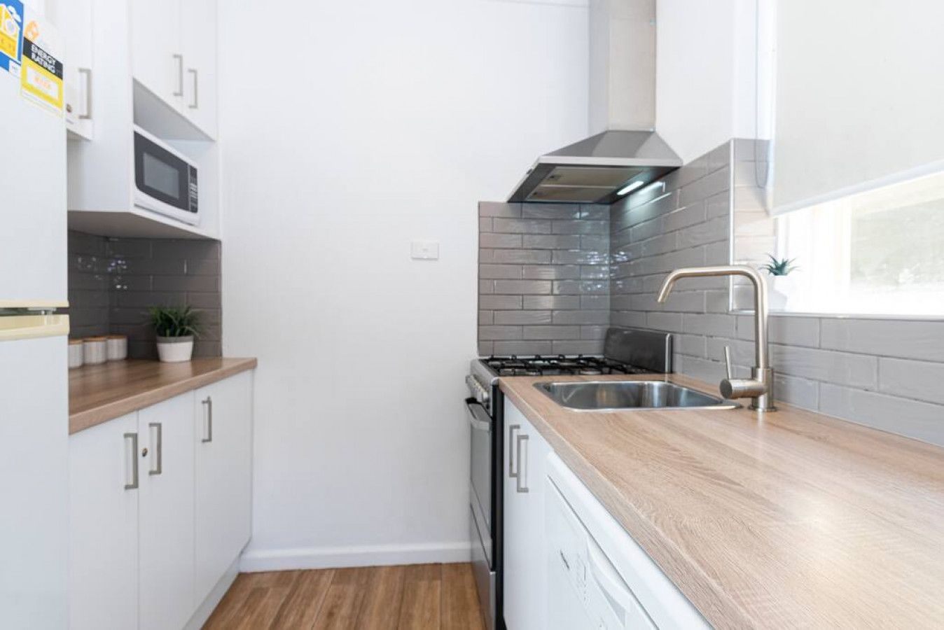 A compact kitchen with white cabinets, a microwave, a stove, and a sink.