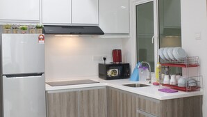 A modern kitchen with white cabinets, a stainless steel refrigerator, a microwave, and a dish rack. - H2H Holland Cottage (Ipoh)