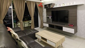 A modern living room with a leather sofa, a wooden coffee table, a flat-screen TV, and a balcony with curtains. - H2H Maison De Luxe (Ipoh)