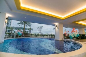 A swimming pool with a view of palm trees and a building in the background. - H2H Maison De Luxe (Ipoh)