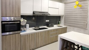 A modern kitchen with a built-in oven, microwave, and a coffee maker on the countertop. - H2H Maison De Luxe (Ipoh)