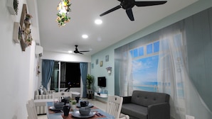 Una sala de estar moderna con comedor, que incluye un sofá, una mesa de comedor con sillas, un ventilador de techo y un ventanal con cortinas.